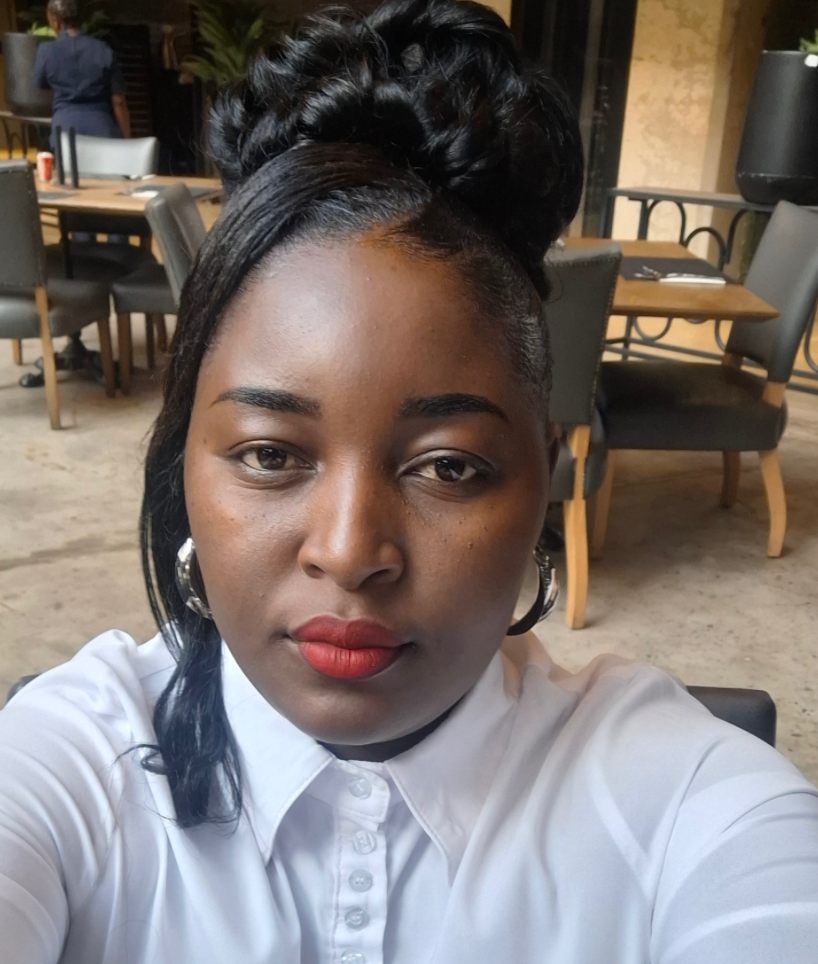 Person photographed indoors, facing the camera in a seated café setting.