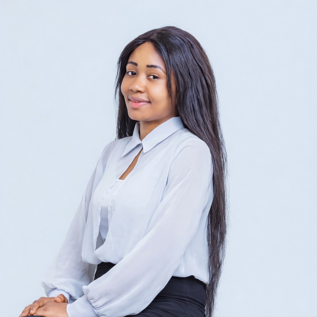 Woman standing indoors wearing a light blouse, photographed against a plain background.