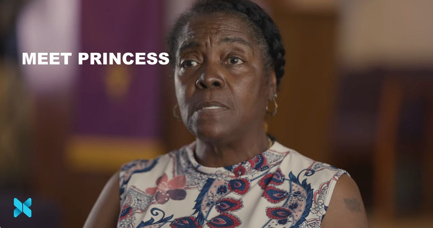 A woman sits indoors speaking to the camera with the words “Meet Princess” displayed on the screen.